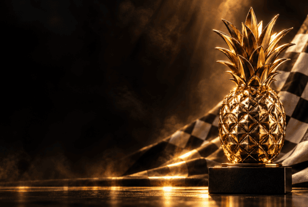 Goldene Ananas auf einem schwarzen Sockel vor einer Zielflagge – Symbolmotiv zur Histo Cup Jahressiegerehrung 2026.